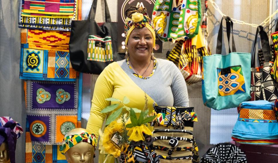 Una mujer afrodescendiente sonríe a cámara en su puesto de la Expo Macamba